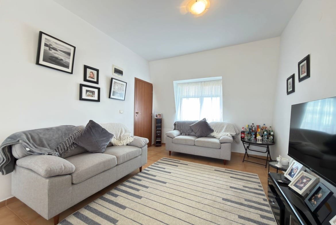 Гостиная с двумя диванами, декоративными рамками на стенах и телевизором, оформленная в нейтральных тонах для продажи недвижимости в Болгарии.