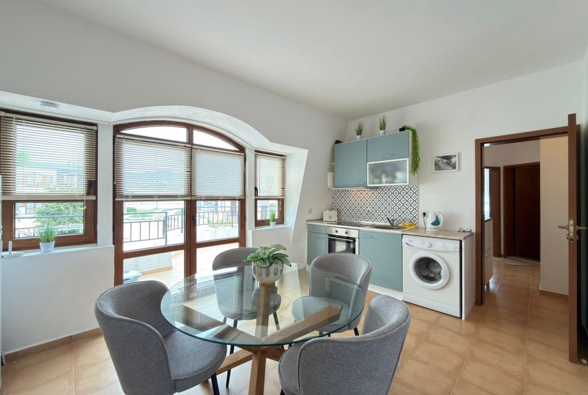 Современная кухня с обеденной зоной, светлыми тонами и большими окнами, с видом на природу в Болгарии.