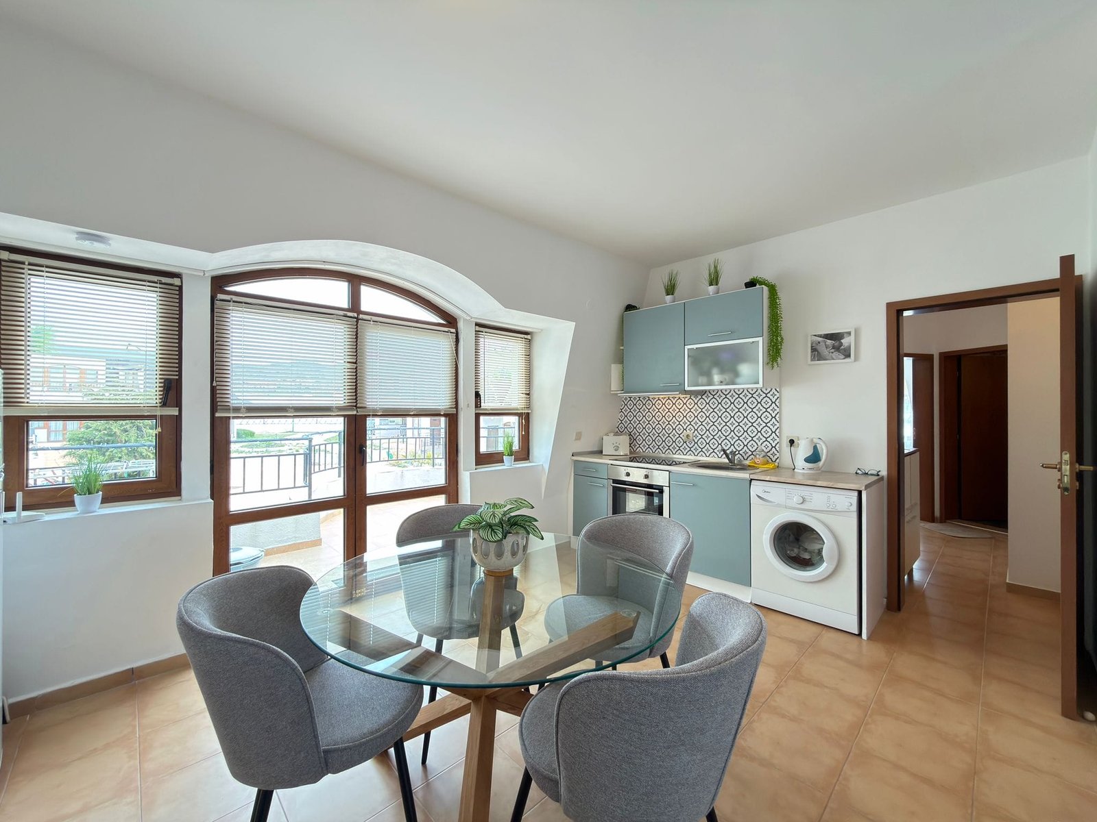 Современная кухня с обеденной зоной, светлыми тонами и большими окнами, с видом на природу в Болгарии.