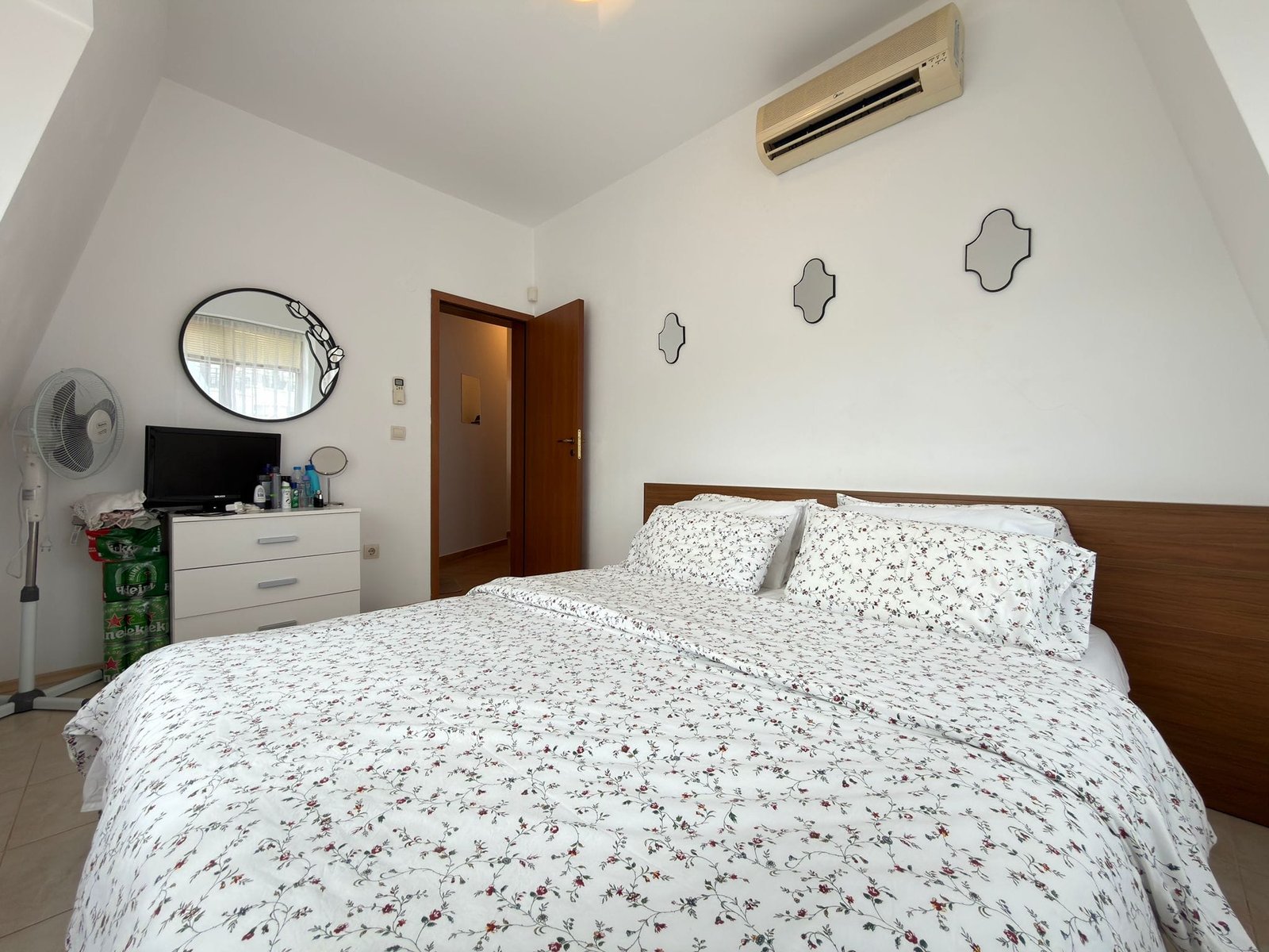 Современная спальня с двуспальной кроватью, белым текстилем и климат-контролем, подходящая для аренды в Болгарии.