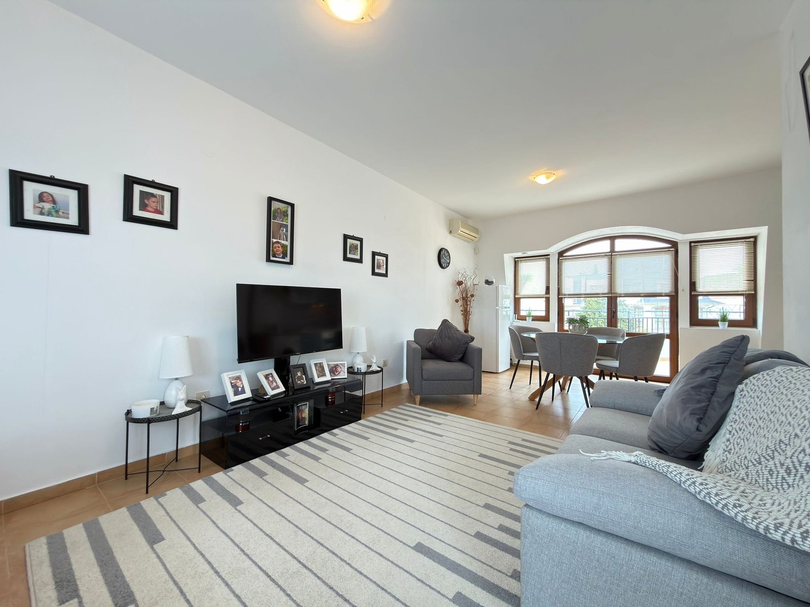 Современный интерьер квартиры в Болгарии с уютной гостиной, телевизором, стульями и декоративными элементами.