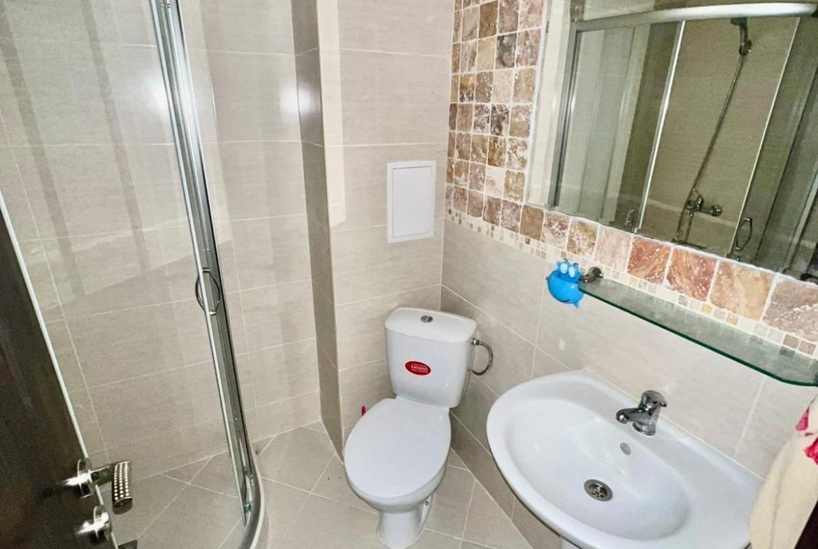 Современная ванная комната с душевой кабиной, унитазом и раковиной, оформленная в светлых тонах, идеальна для недвижимости в Болгарии.