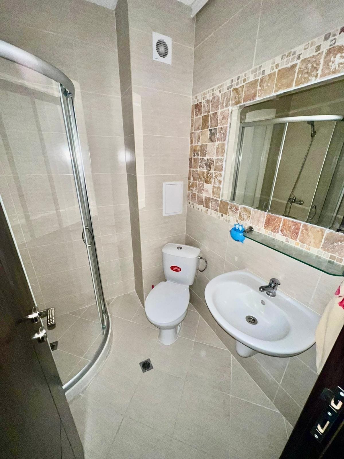 Современная ванная комната с душевой кабиной, унитазом и раковиной, оформленная в светлых тонах, идеальна для недвижимости в Болгарии.