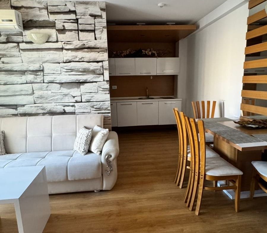 Современный интерьер квартиры в Болгарии с мягким диваном и обеденным столом, оформленный в нейтральных тонах.