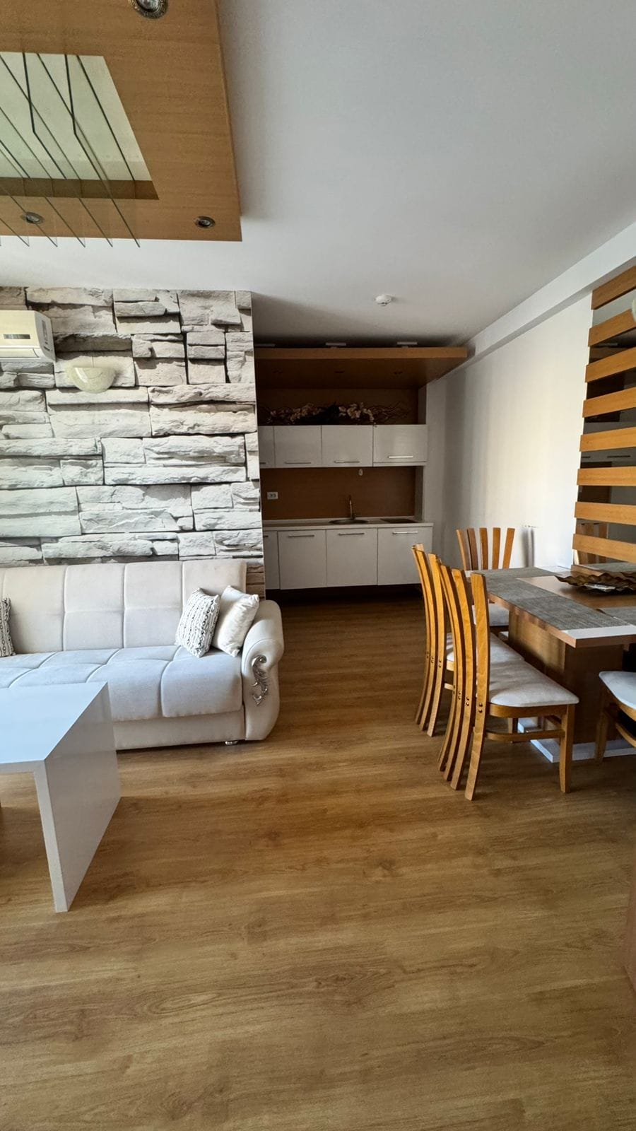 Современный интерьер квартиры в Болгарии с мягким диваном и обеденным столом, оформленный в нейтральных тонах.