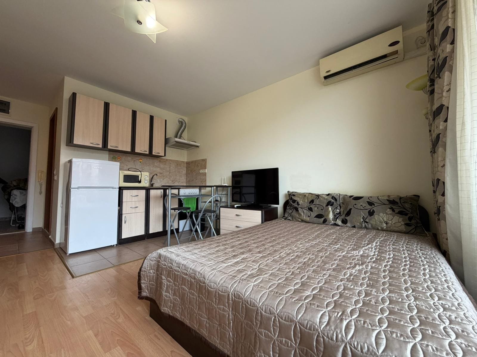 Современная квартира-студия с кухней и ТВ в светлых тонах Современная квартира в Болгарии с кухней, зоной для отдыха и кондиционером, идеальна для покупки или аренды.