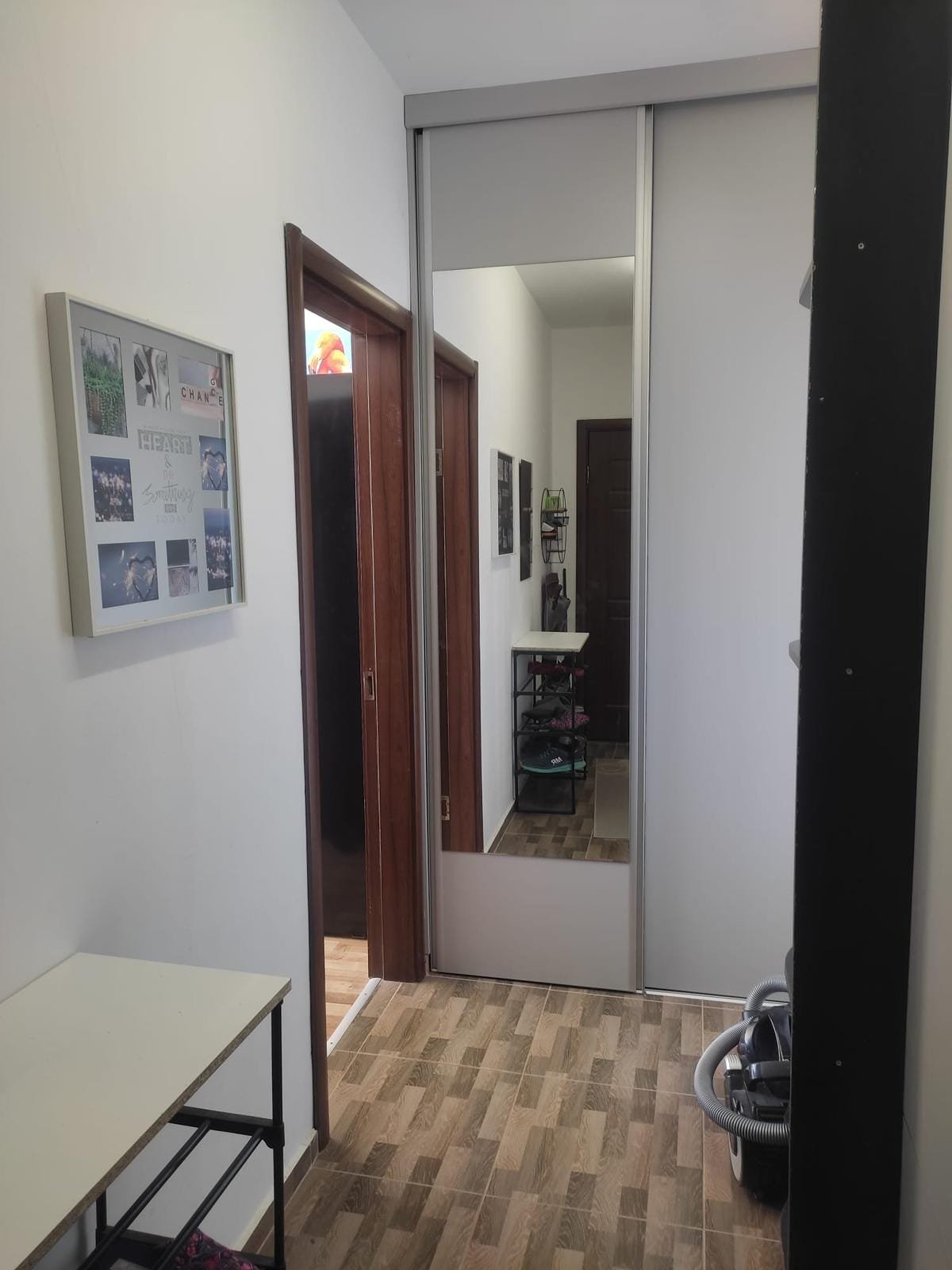 Современный коридор с зеркальным шкафом, светлыми стенами и деревянным полом, идеально подходит для покупки недвижимости в Болгарии.