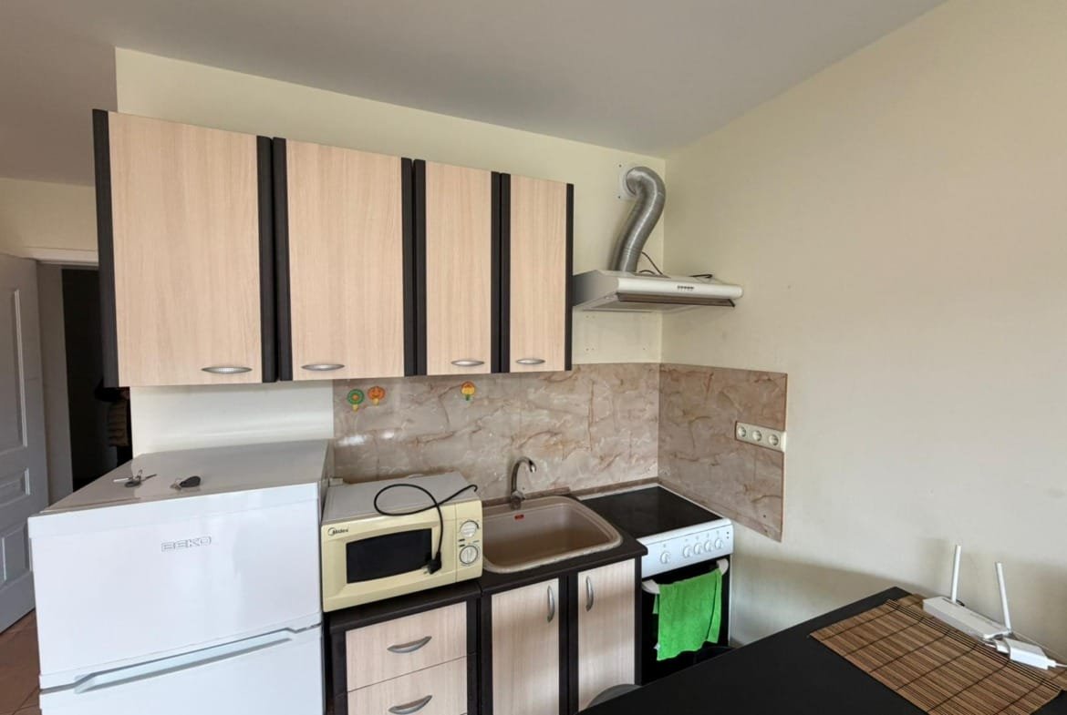 Современная кухня с холодильником, плитой, микроволновкой и столешницей, идеально подходящая для покупки недвижимости в Болгарии.