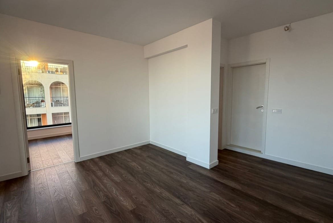 Современная квартира в Болгарии с светлыми стенами, светлым паркетом и выходом на балкон, идеальна для покупки или аренды.