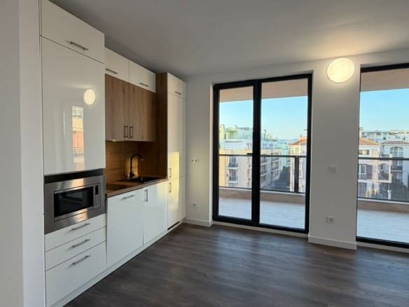 Современная кухня с белыми шкафами и деревянными акцентами, большие окна с видом на городской пейзаж в Болгарии.