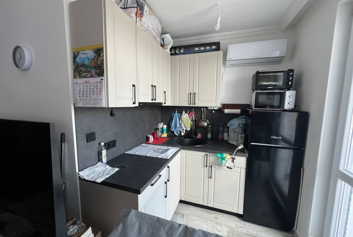 Кухня в квартире с современным дизайном, черными и светлыми элементами, холодильником и техникой, готовая к продаже в Болгарии.