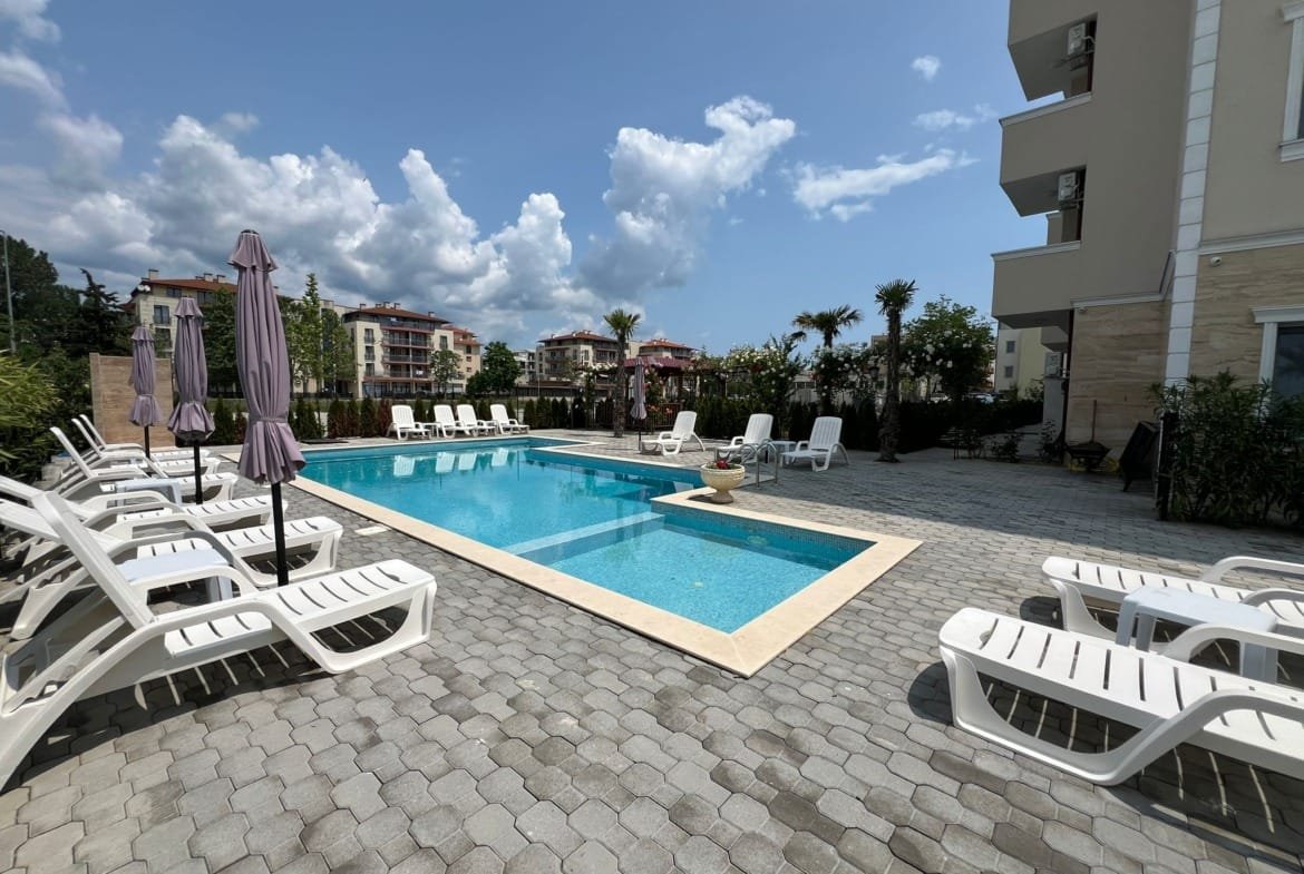 Площадка с бассейном и шезлонгами в жилом комплексе Болгарии, идеальное место для отдыха и покупки недвижимости у моря.