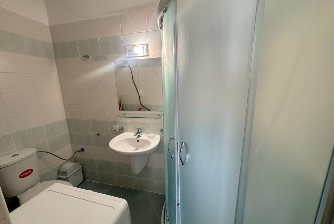 Функциональная ванная с душевой кабиной, унитазом и раковиной, оформленная в светлых тонах, идеальна для продажи недвижимости в Болгарии.