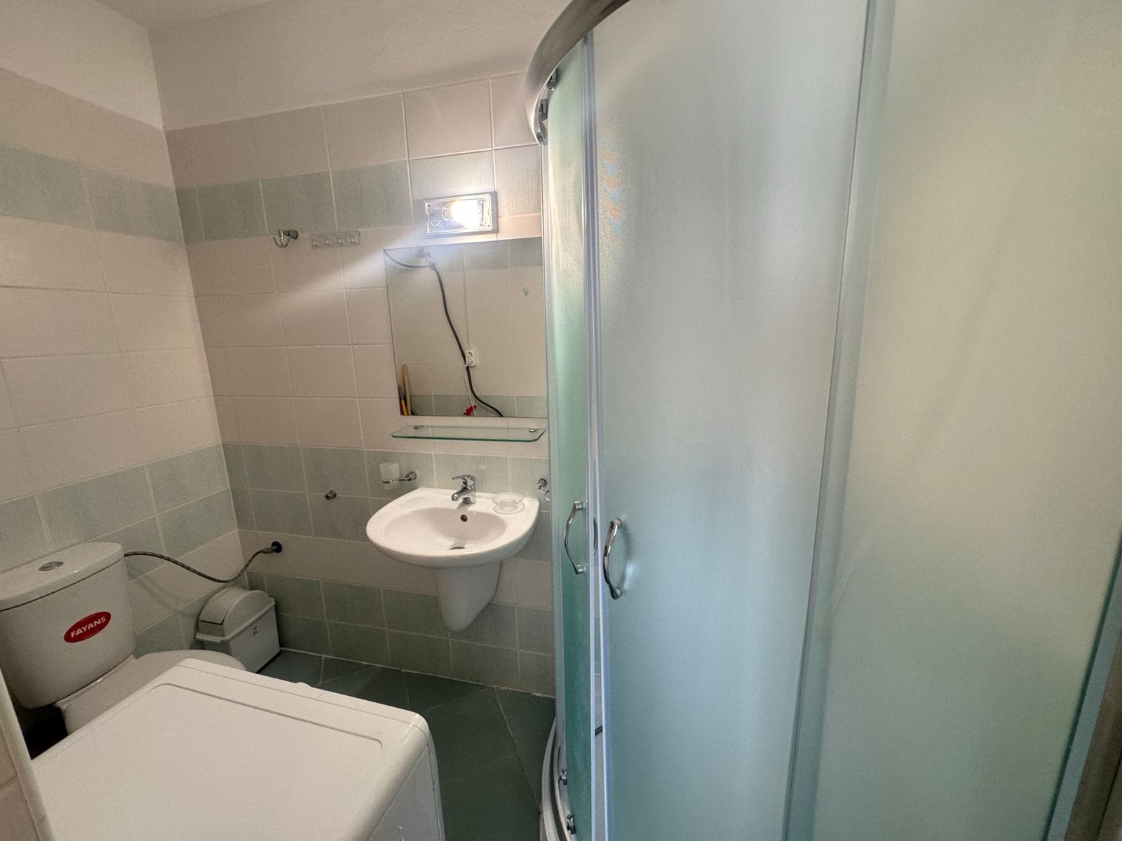 Функциональная ванная с душевой кабиной, унитазом и раковиной, оформленная в светлых тонах, идеальна для продажи недвижимости в Болгарии.