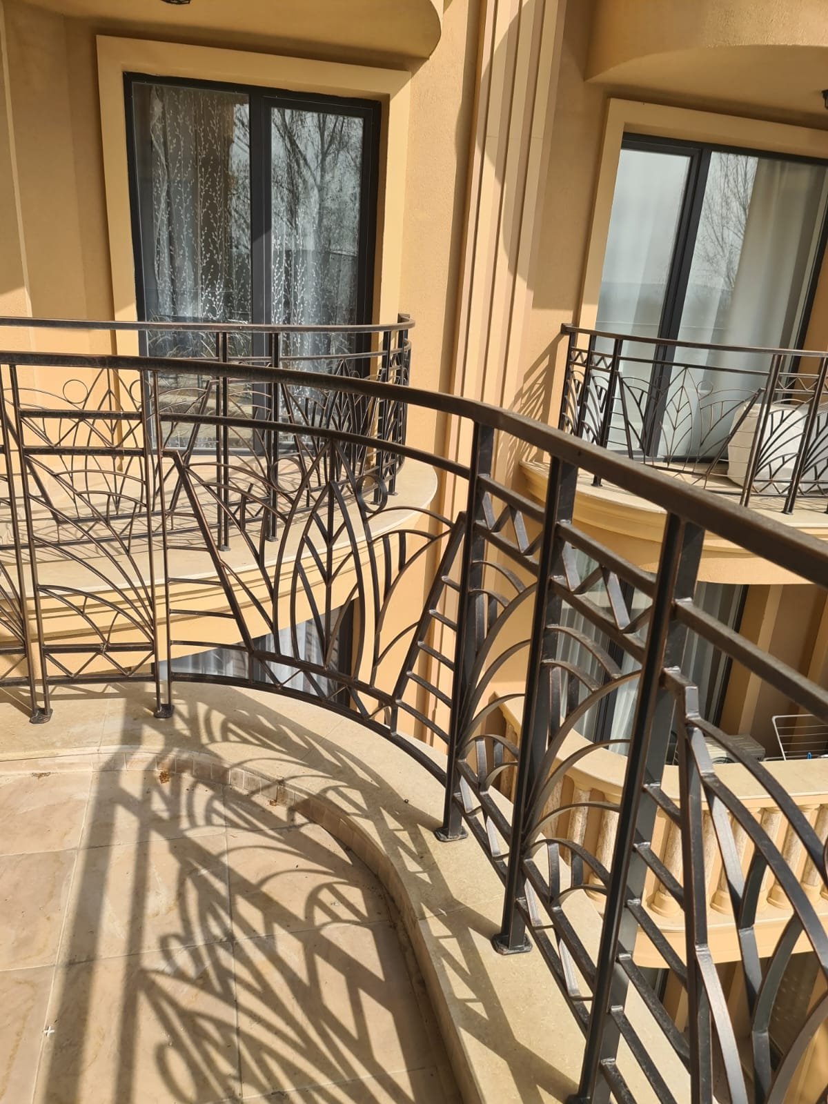 Балкон с кованым ограждением и вид на окна, отражающие стиль жилья в Болгарии для покупателей недвижимости.