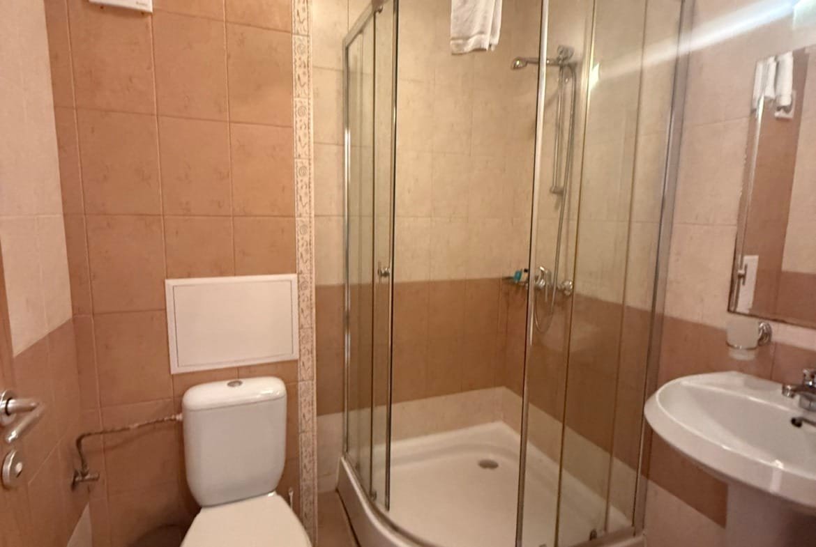 Современная ванная комната с душевой кабиной, унитазом и умывальником. Интерьер в нейтральных тонах, чистота и комфорт.