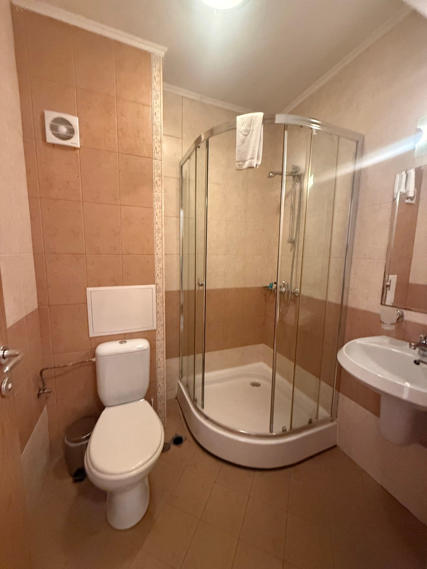 Современная ванная комната с душевой кабиной, унитазом и умывальником. Интерьер в нейтральных тонах, чистота и комфорт.