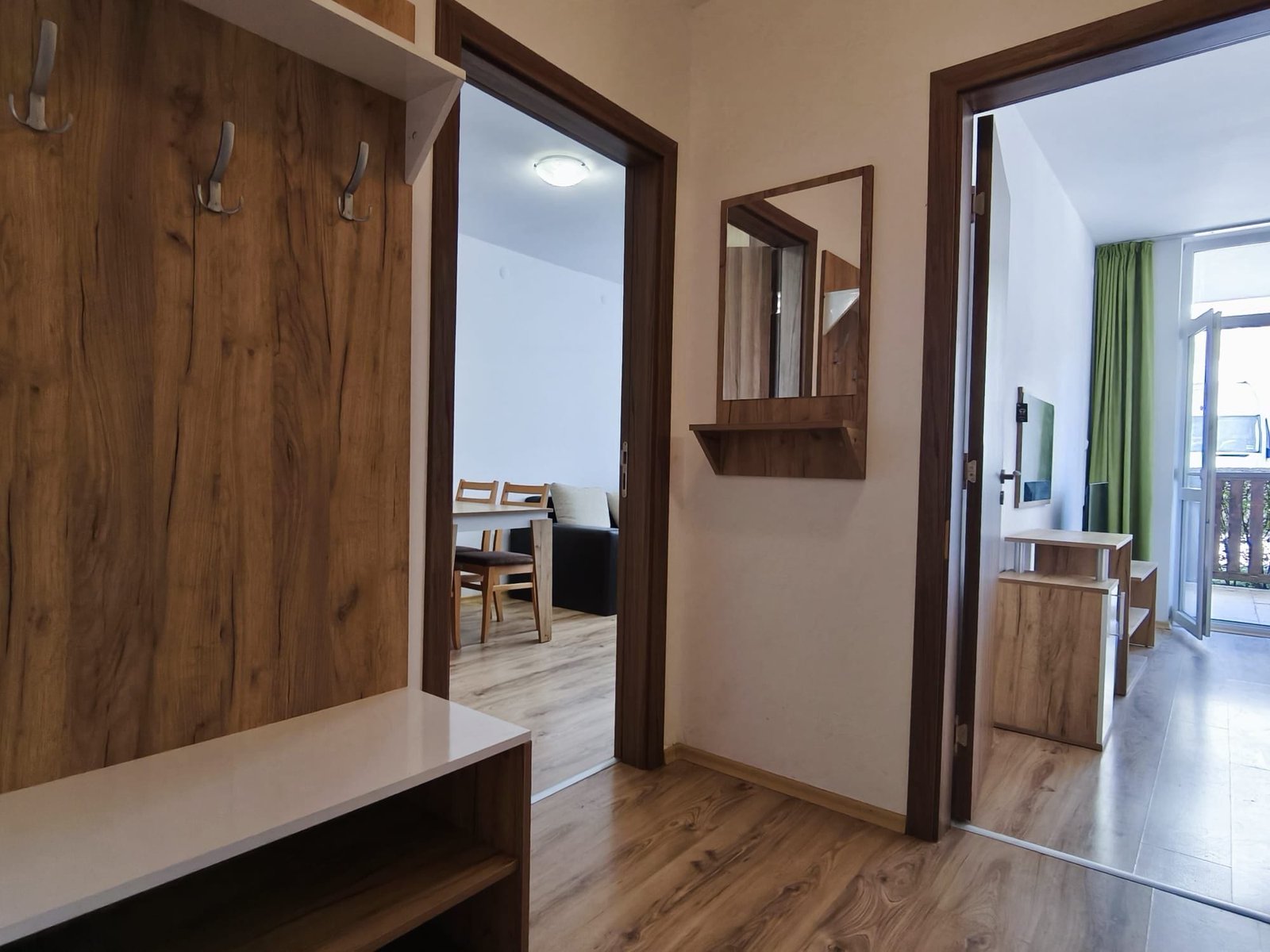 Современный интерьер прихожей с деревянным декором и светлыми тонами. Современный интерьер квартиры в Болгарии с прихожей, обеденной зоной и выходом на балкон из комнаты.