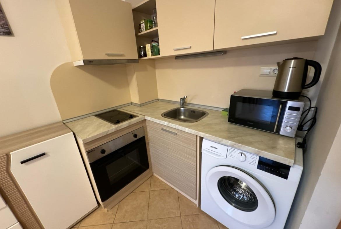 Современная кухня с плитой, микроволновой печью и стиральной машиной, идеальная для комфортной жизни в Болгарии.
