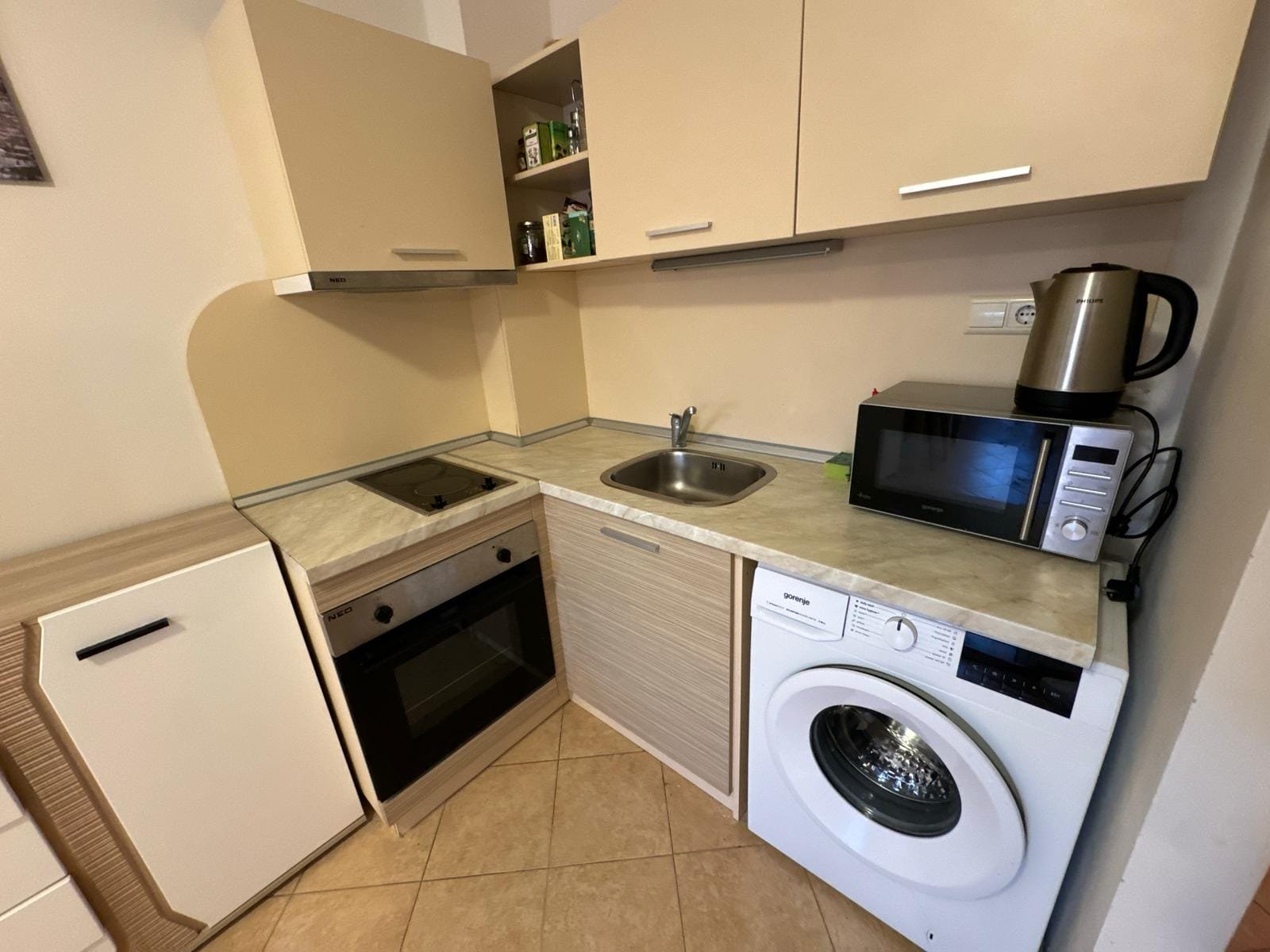 Современная кухня с техникой: плита, микроволновка и стиральная машина Современная кухня с плитой, микроволновой печью и стиральной машиной, идеальная для комфортной жизни в Болгарии.