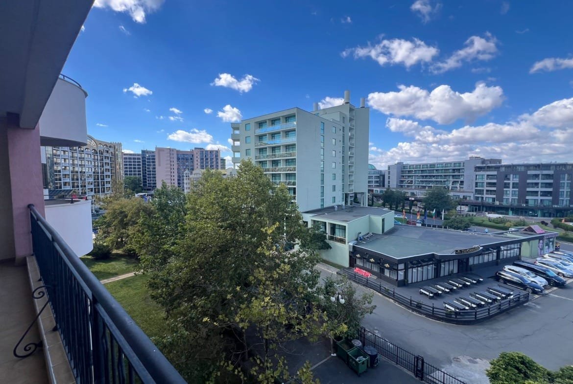 Балконный вид на жилые и коммерческие здания в Болгарии, зелёные насаждения и морская атмосфера. Продажа недвижимости.