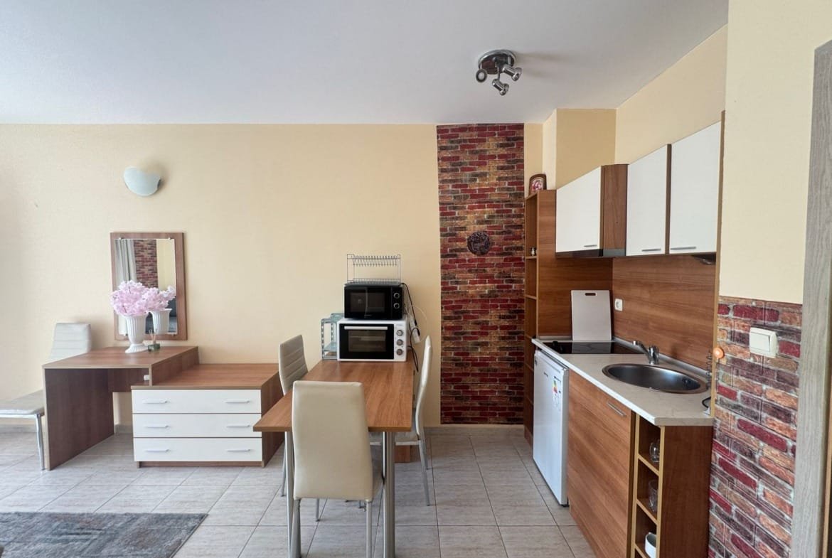 Современная кухня-гостиная с обеденным столом, бытовой техникой и уютным интерьером для комфортной жизни в Болгарии.