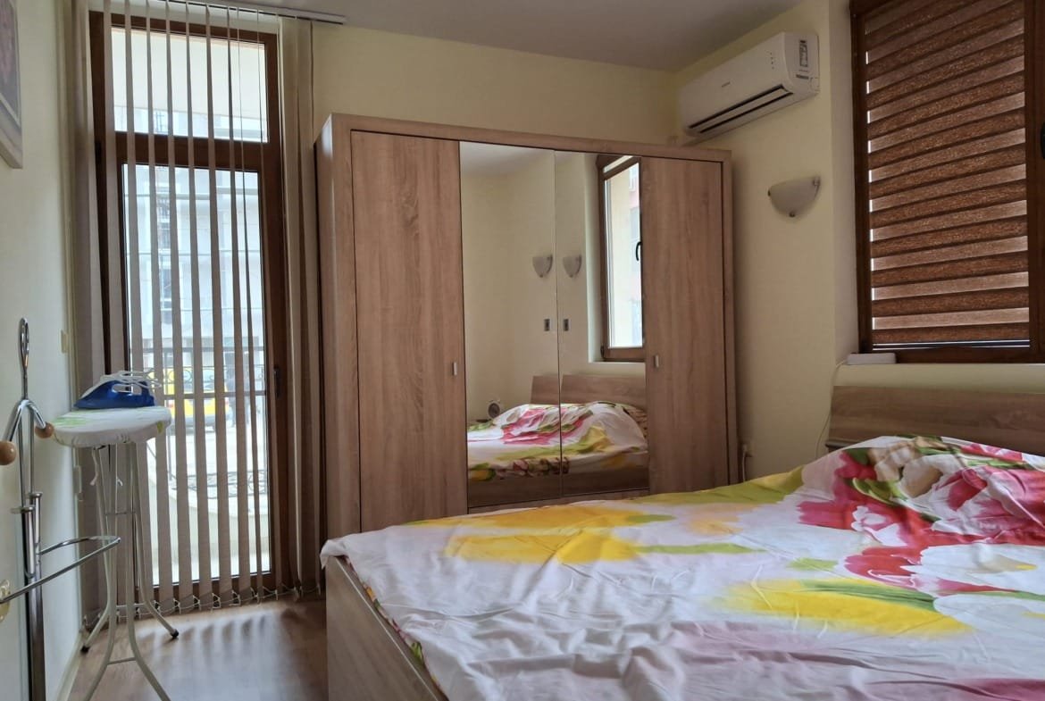 Современная спальня с двуспальной кроватью, деревянным шкафом и окнами с жалюзи, светлые тона и уютный интерьер.