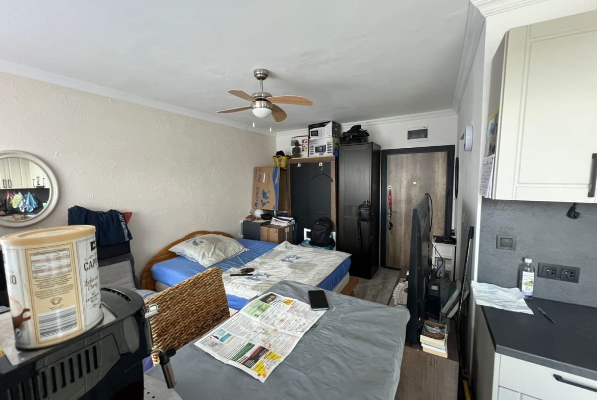 Уютная комната с двуспальной кроватью, кухонным уголком и мебелью, подходящая для продажи недвижимости в Болгарии.