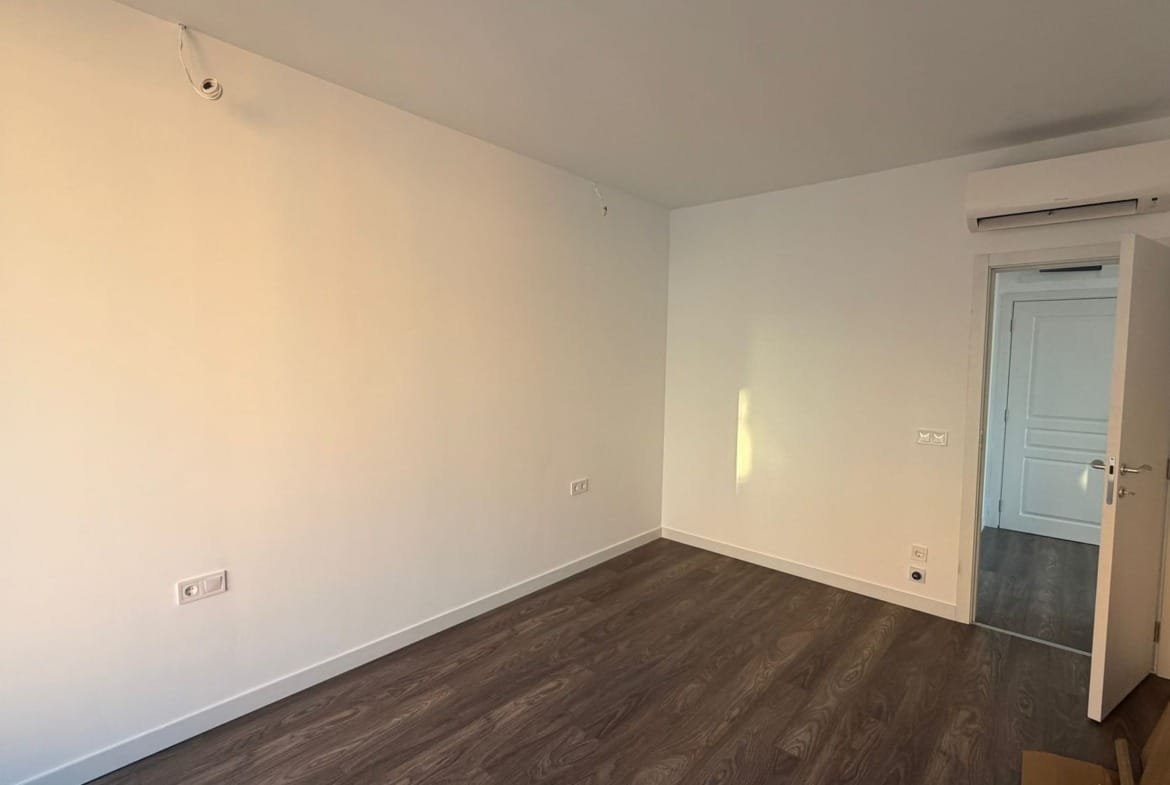 Светлое пустое помещение с белыми стенами и деревянным полом, готовое для обустройства под жилье в Болгарии.