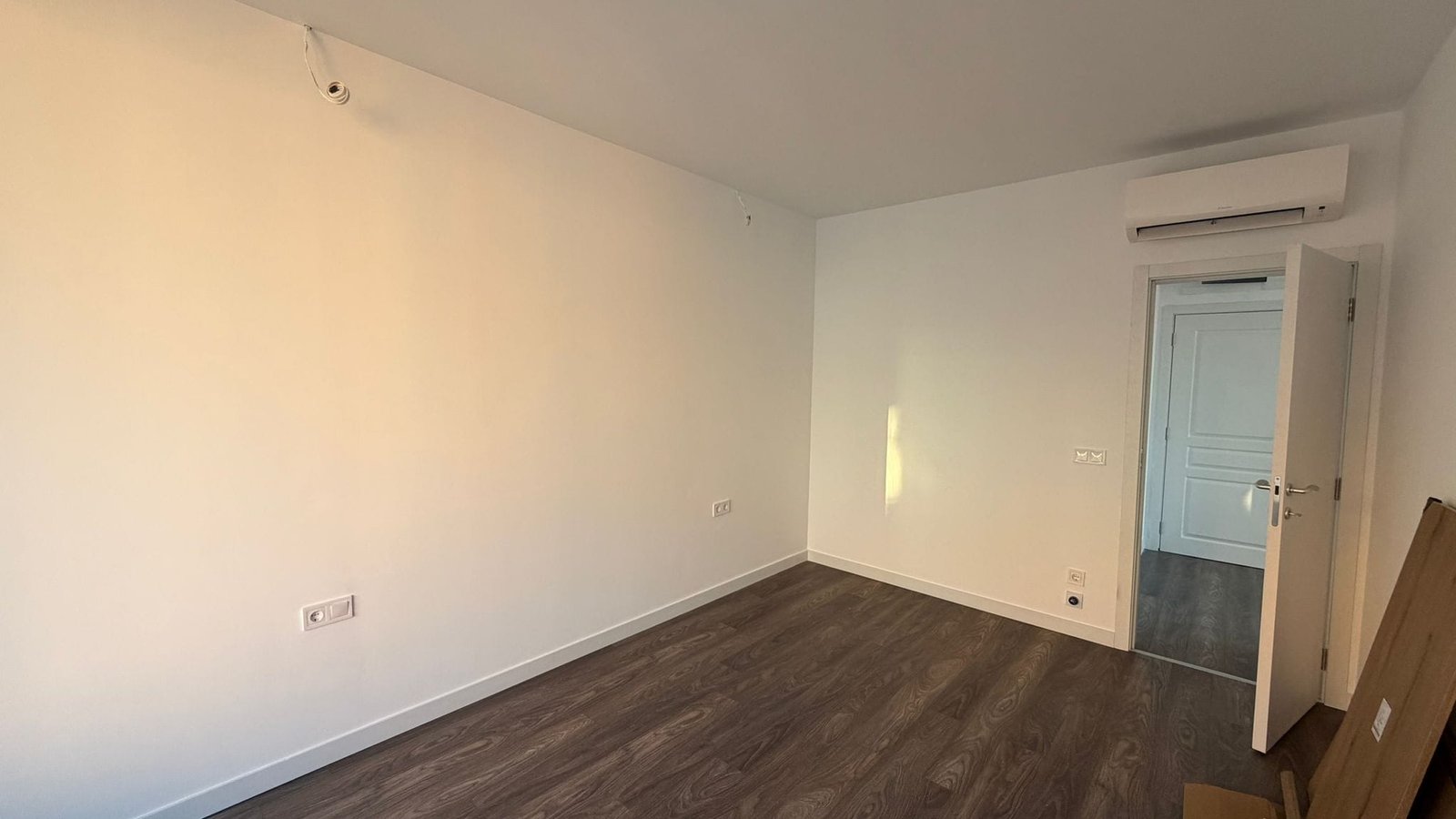 Пустая комната с хорошим освещением и современным ремонтом Светлое пустое помещение с белыми стенами и деревянным полом, готовое для обустройства под жилье в Болгарии.