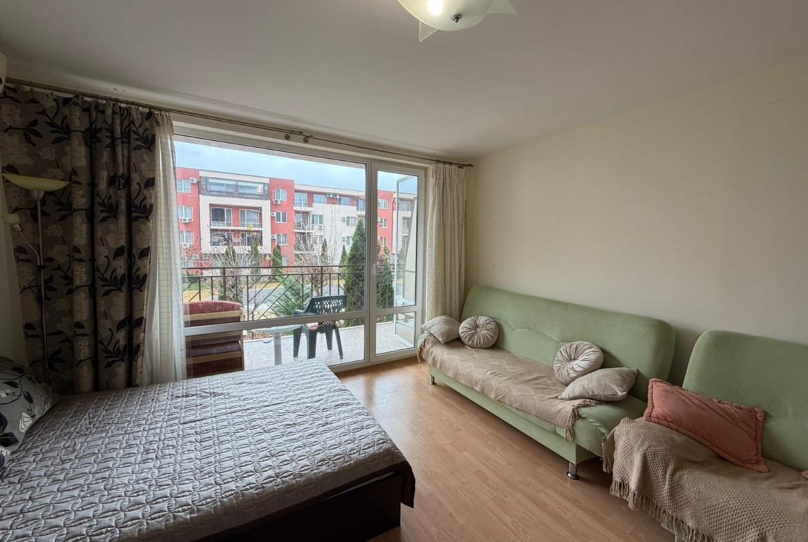 Светлая комната с балконом, кроватью и диваном, идеально подходит для отдыха и жизни в Болгарии.