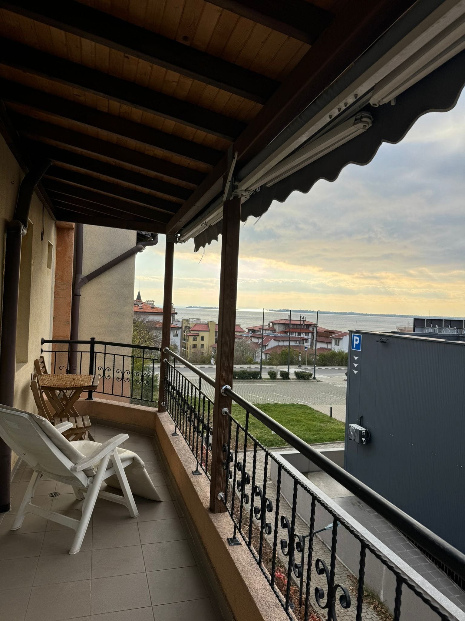 Балкон с видом на море и город в курортной зоне Балкон с лежаком и столиком, вид на море и жилые дома, идеальное место для отдыха в Болгарии.