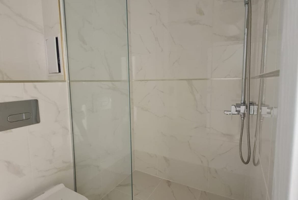 Современная ванная комната с душевой кабиной, унитазом и стильной плиткой, идеально подходящая для покупки недвижимости в Болгарии.