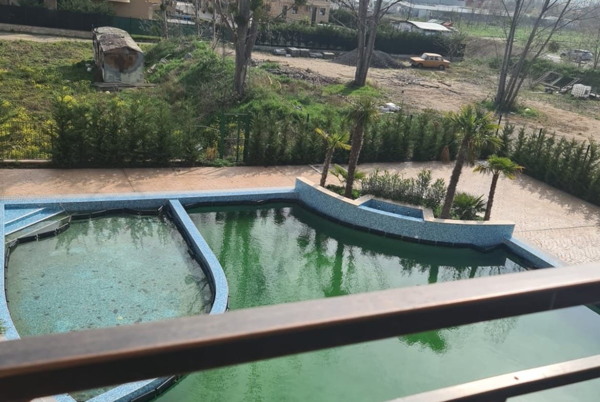 Панорамный вид на зеленоватый бассейн и окружающую территорию с новыми зданиями в Болгарии для продажи недвижимости.