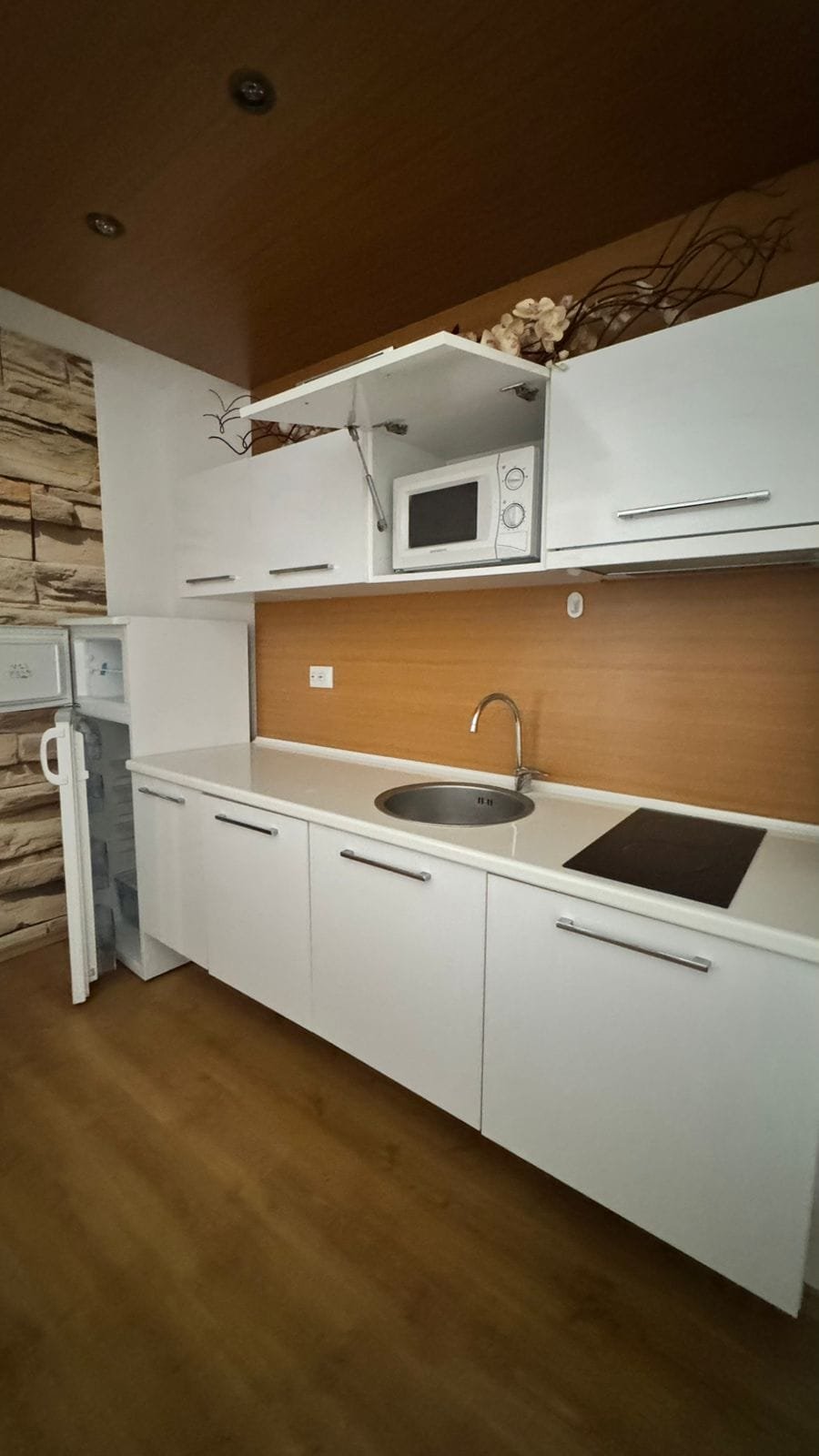 Современная кухня с белыми шкафами, встроенной мойкой и бытовой техникой, идеальная для покупки недвижимости в Болгарии.