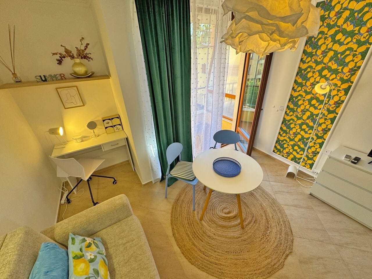 Современная гостиная с уютным интерьером, столом и стульями, светлым текстилем и яркой желтой акцентной стеной.