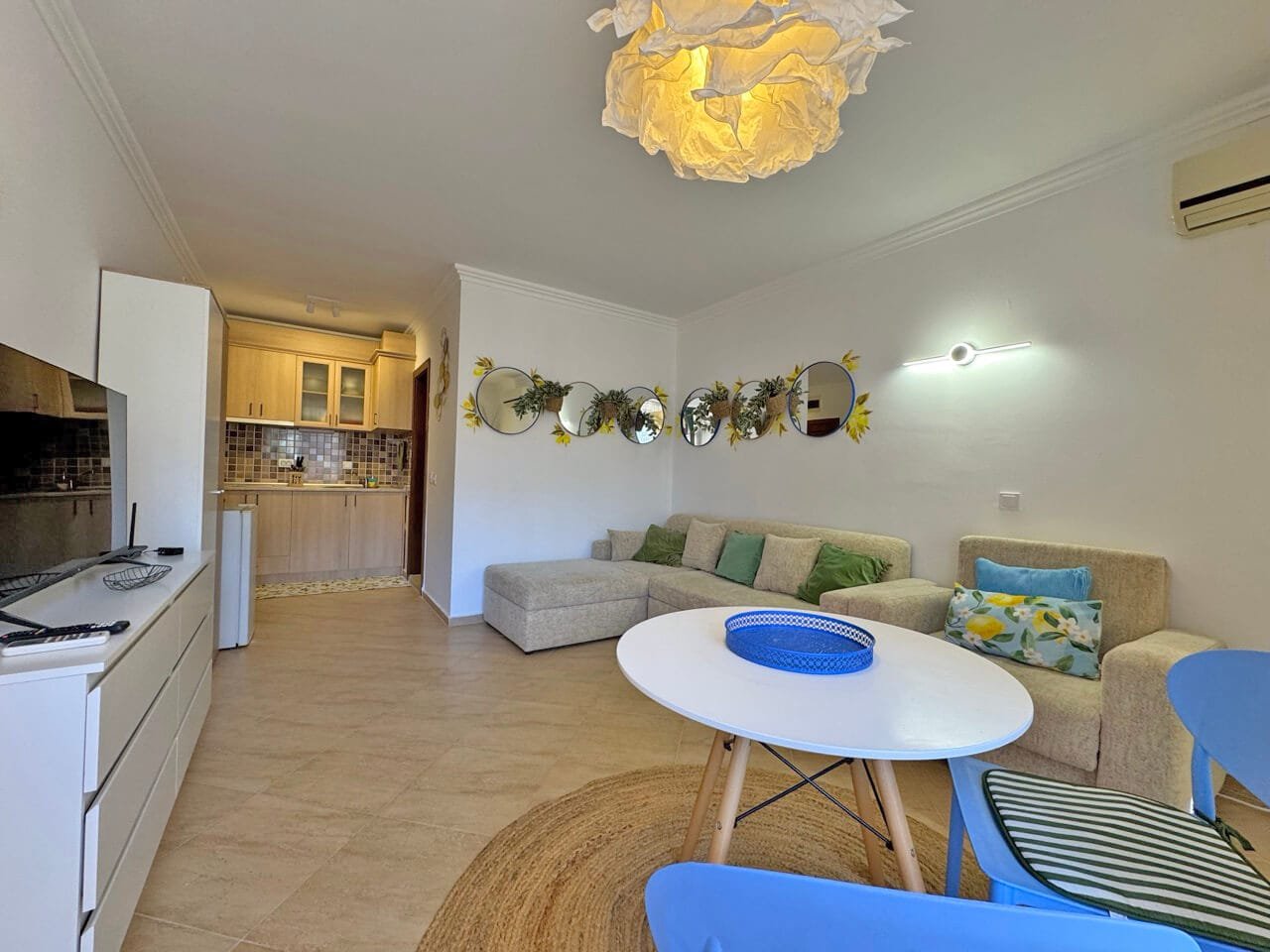 Современная гостиная с уютным диваном, яркими акцентами и кухонной зоной, идеально подходит для апартаментов в Болгарии.