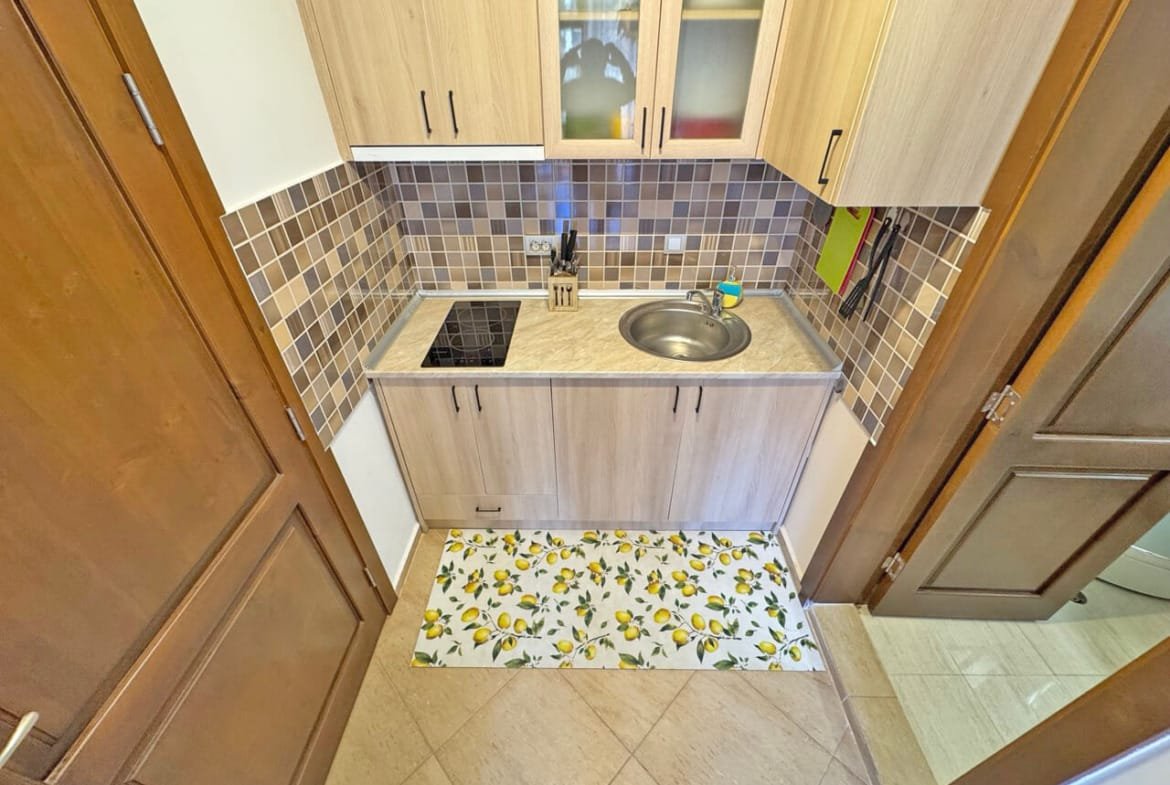 Кухня с современной отделкой, плиткой в бежево-коричневых тонах, укомплектована встроенной техникой и мойкой. Подходит для квартиры в Болгарии.