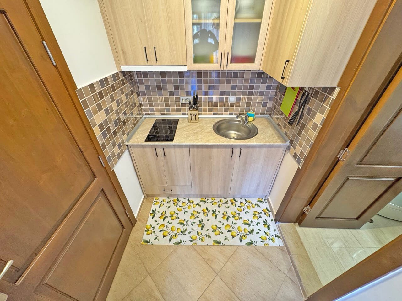 Кухня с современной отделкой, плиткой в бежево-коричневых тонах, укомплектована встроенной техникой и мойкой. Подходит для квартиры в Болгарии.