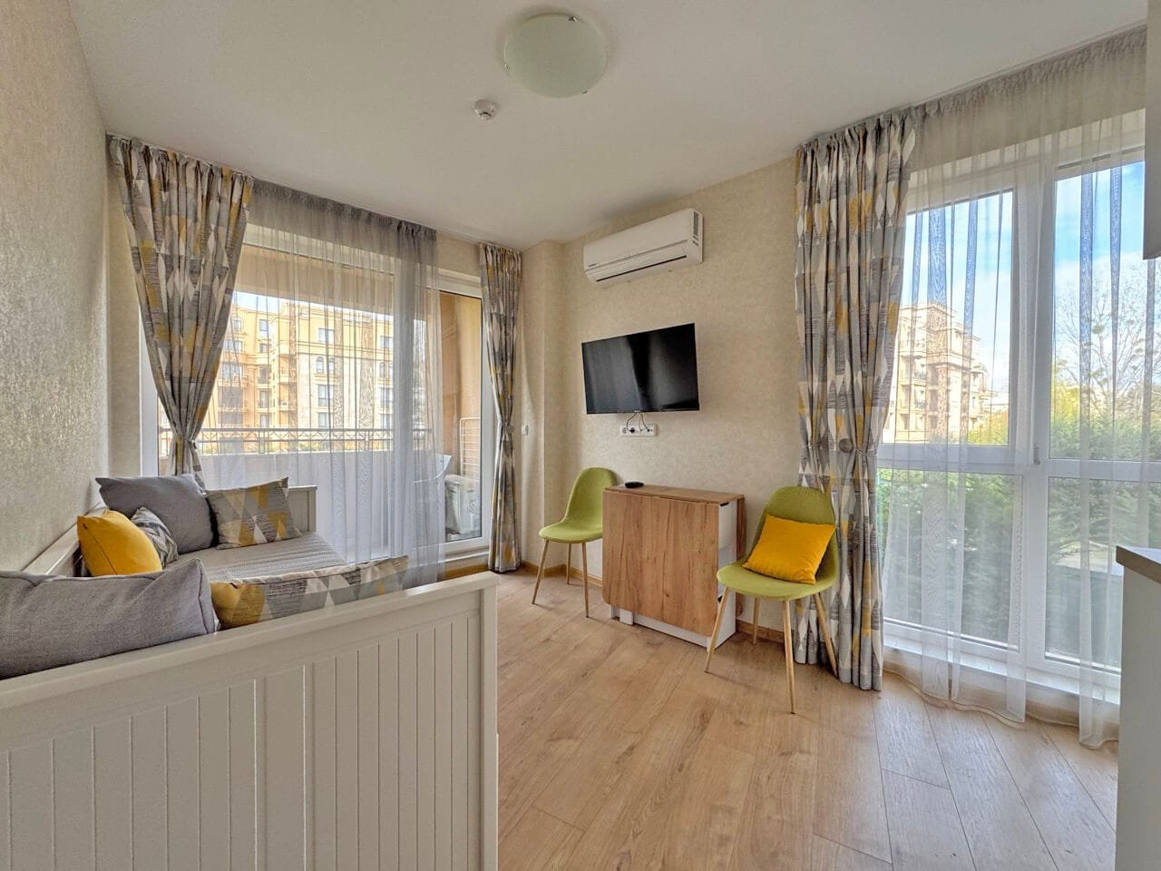 Современная гостиная с балконом и телевизором в квартире. Современная гостиная с мягким уголком, телевизором и выходом на террасу, апартаменты у моря