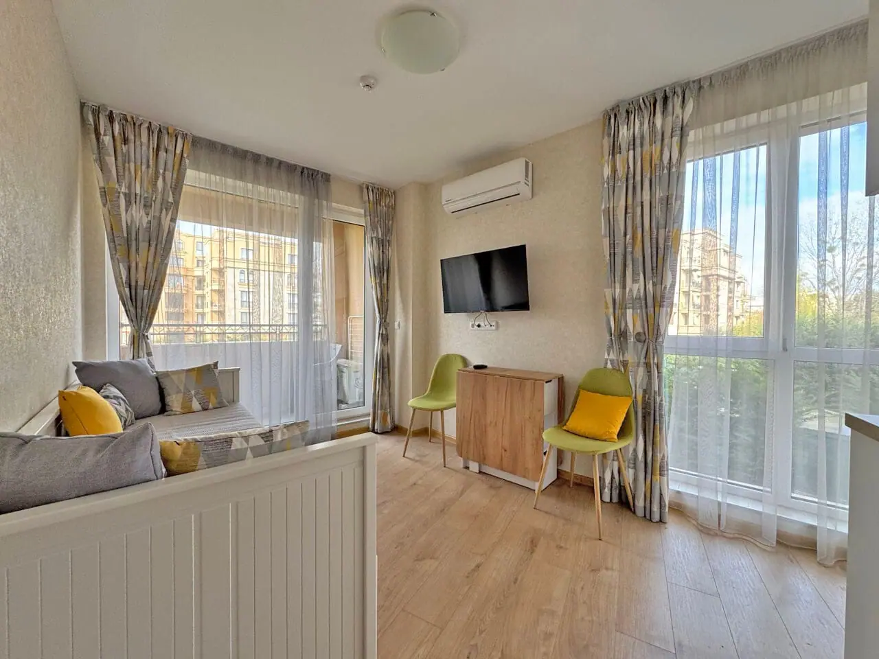 Современная гостиная с балконом и телевизором в квартире. Современная гостиная с мягким уголком, телевизором и выходом на террасу, апартаменты у моря