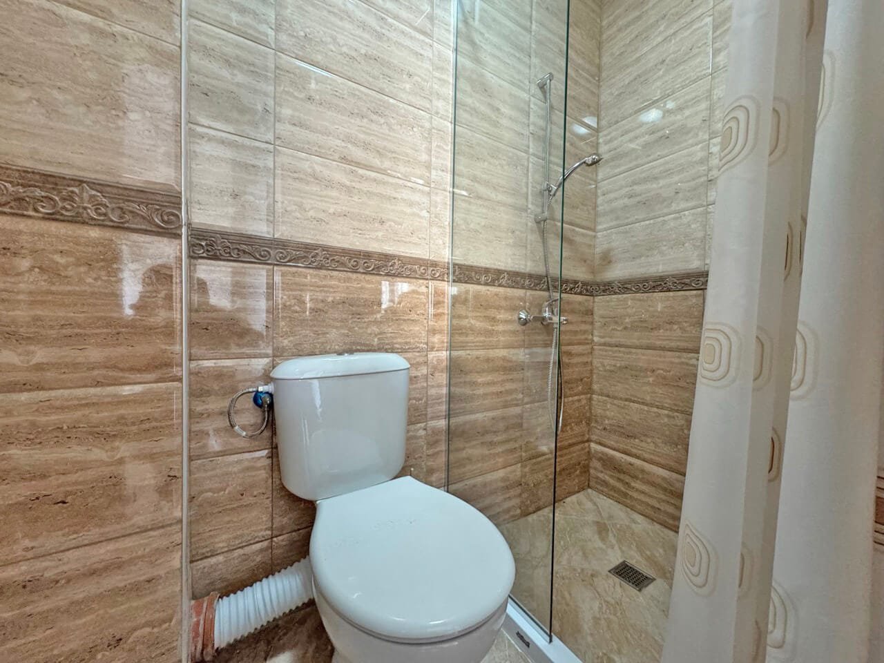 Современная ванная комната с душем и унитазом в ней. Современная ванная комната с душевой кабиной, отделка в светлых тонах, идеальна для апартаментов у моря в Болгарии.