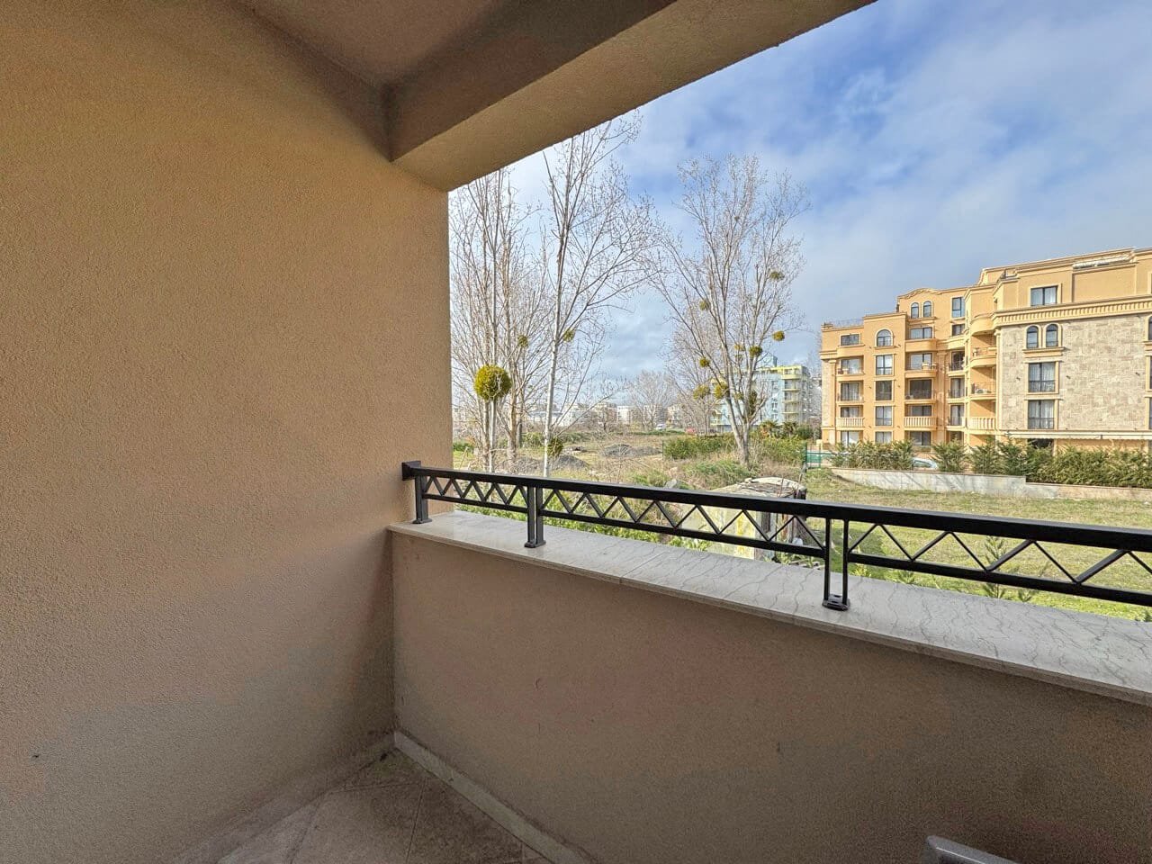 Балкон с видом на парк и жилые здания в ясный день Терраса с видом на зеленый двор и жилой комплекс, расположенный в районе Святого Власа, идеальная для комфортного проживания.