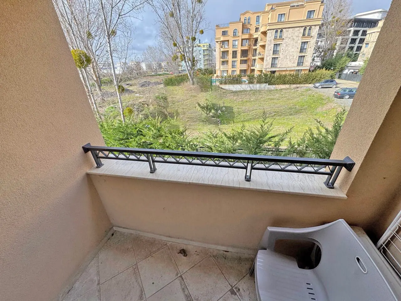 Балкон с видом на зеленую территорию и здания. Балкон с видом на зелёный участок и жилые дома в Болгарии, идеальный для апартаментов у моря.