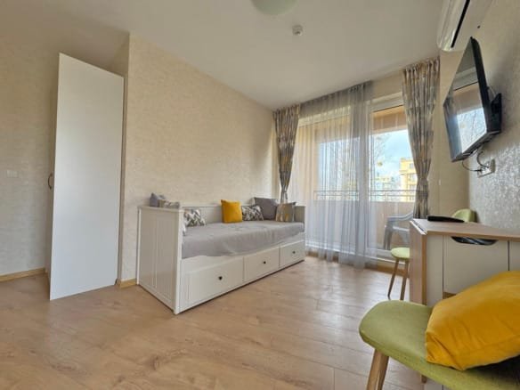 Современная гостиная с раскладным диваном, столиком и балконом, в квартире, идеальна для отдыха у моря.