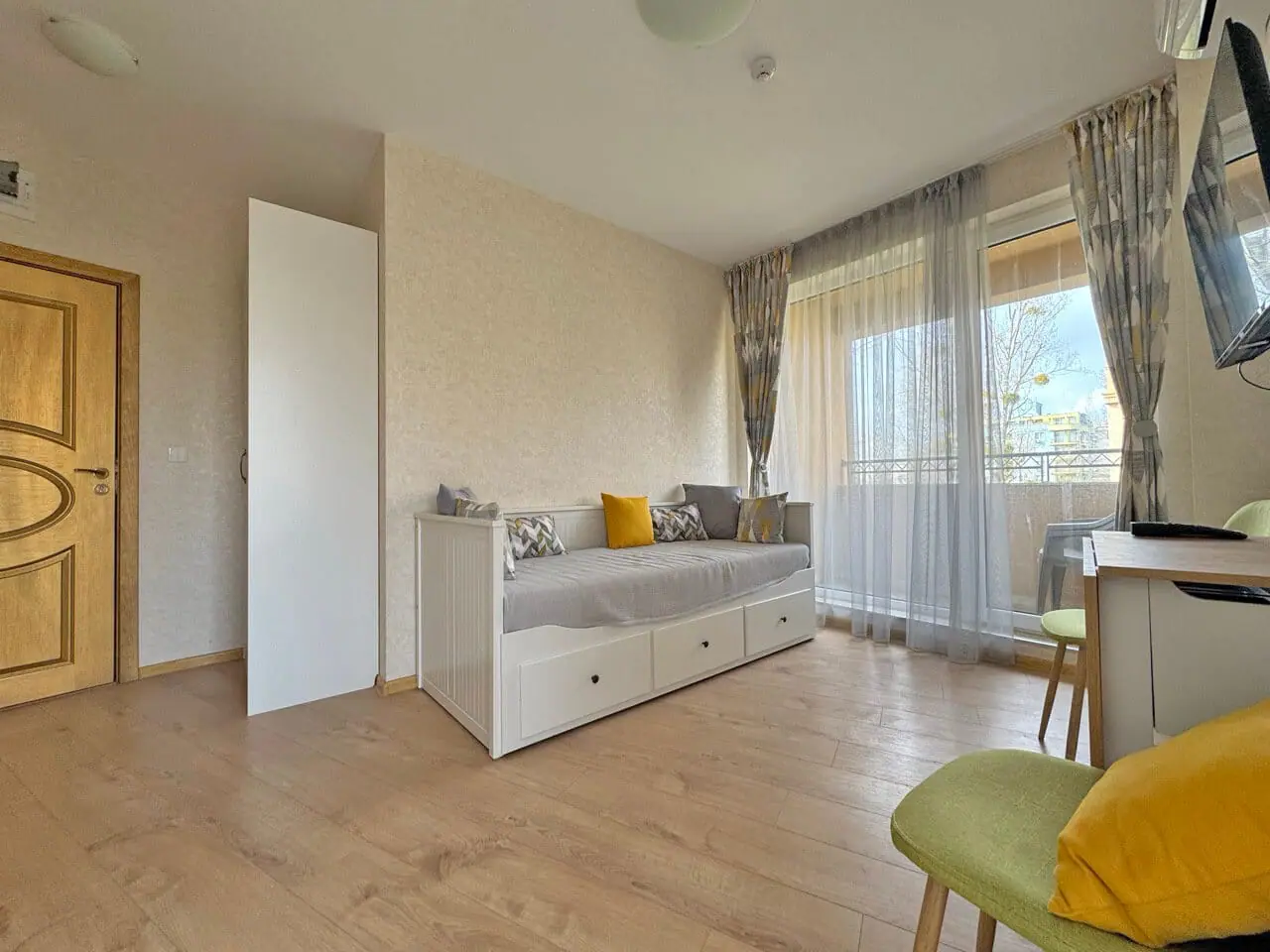 Современная комната с балконом и уютной мебелью Современная квартира с уютной гостиной, балконом и светлым интерьером, идеально подходит для отдыха у моря.