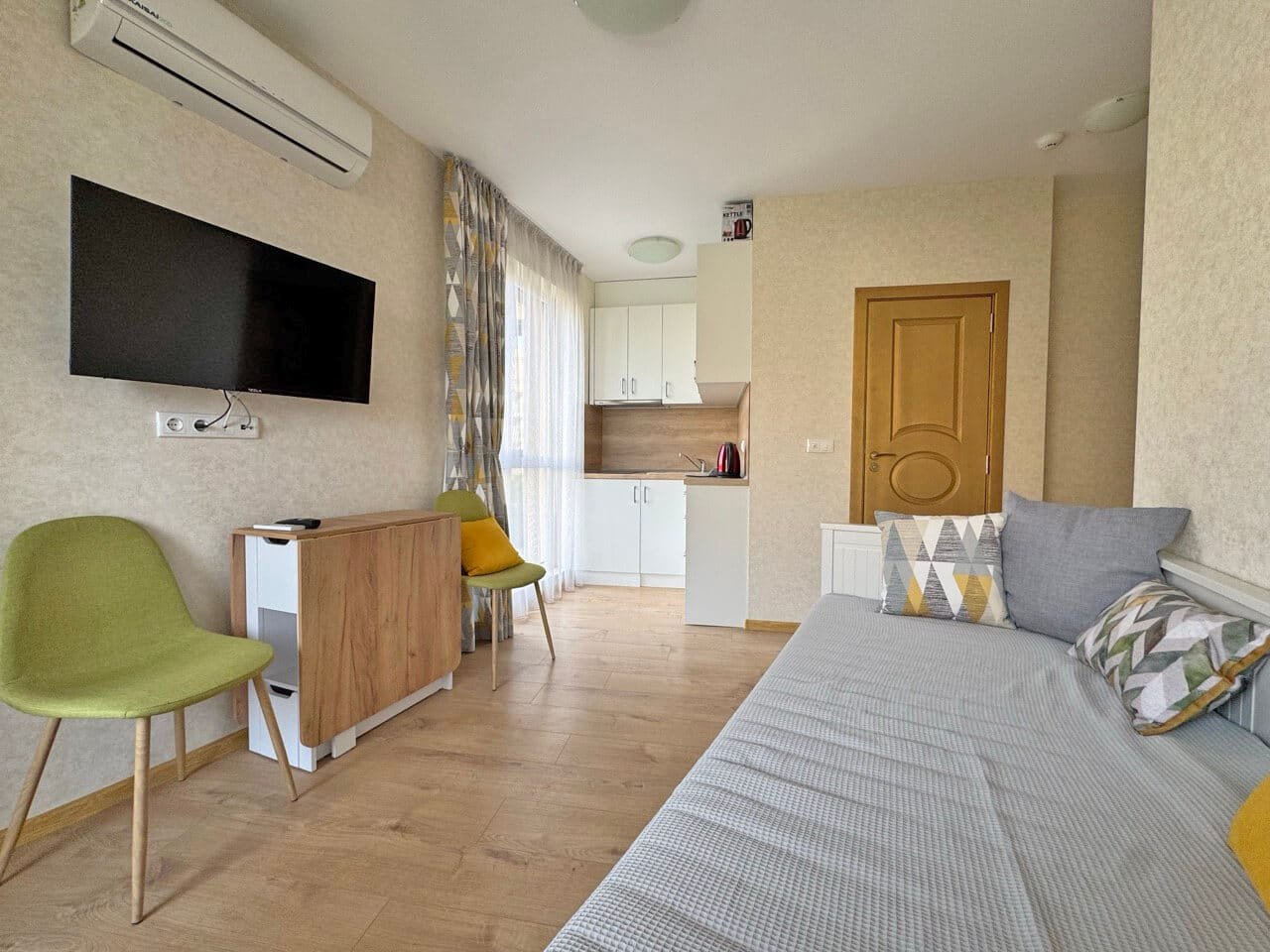 Современный стильный интерьер квартиры-студии с кухней и диваном Современная квартира-студия с кухонной зоной, гостиной и видом на море, обставленная стильной мебелью.