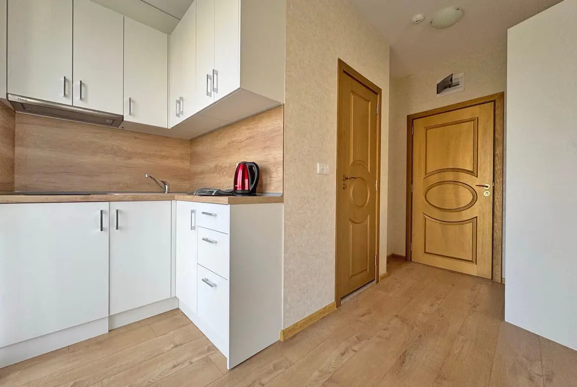 Современная кухня в квартире, с деревянными полу и светлой мебелью, ждет новых владельцев.