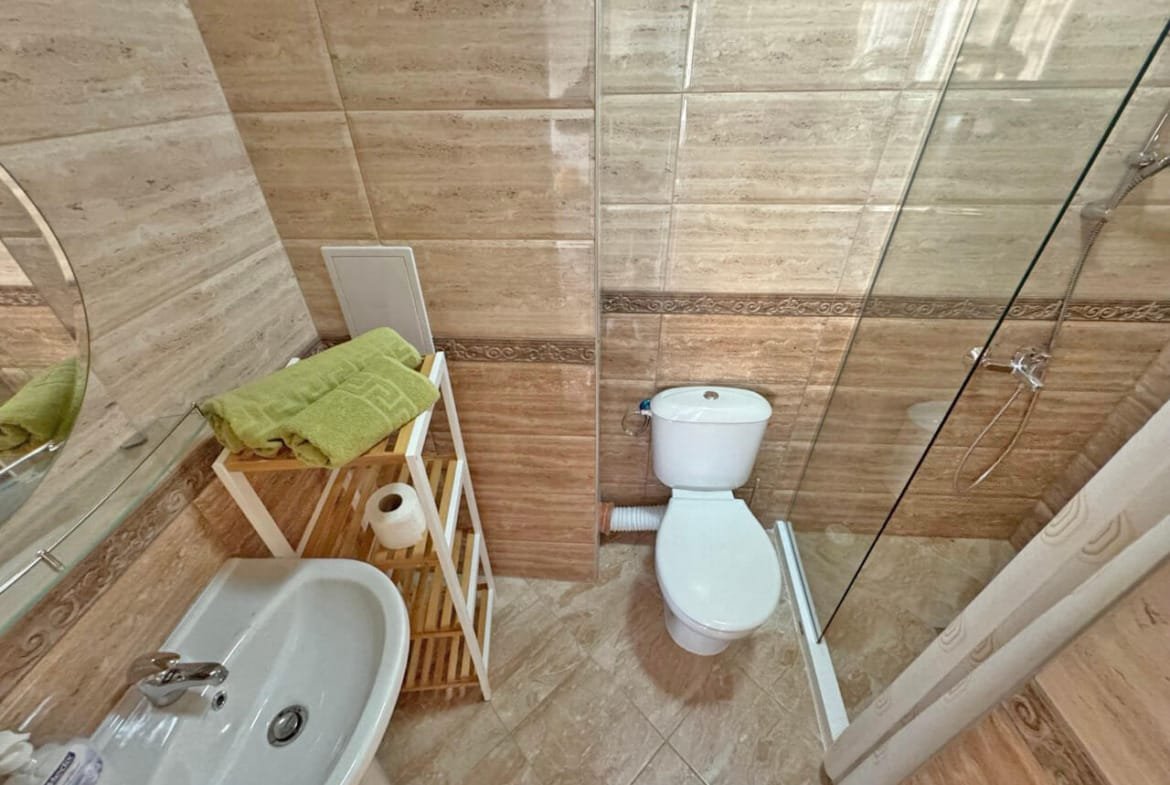 Современная ванная комната с душевой кабиной, умывальником и стильным декором, идеальная для апартаментов в Болгарии.