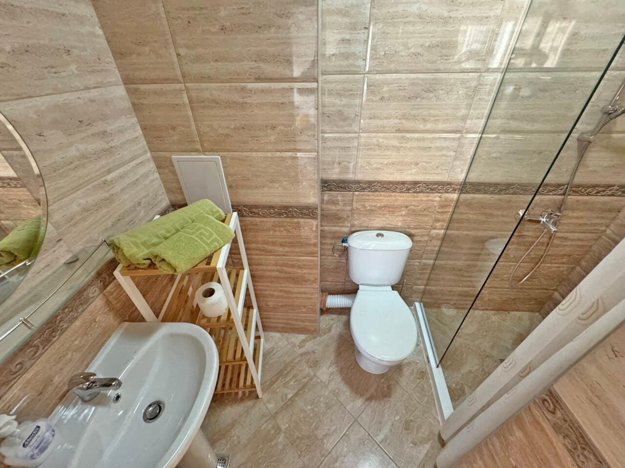 Современная ванная комната с душевой и туалетом, стильный интерьер Современная ванная комната с душевой кабиной, умывальником и стильным декором, идеальная для апартаментов в Болгарии.